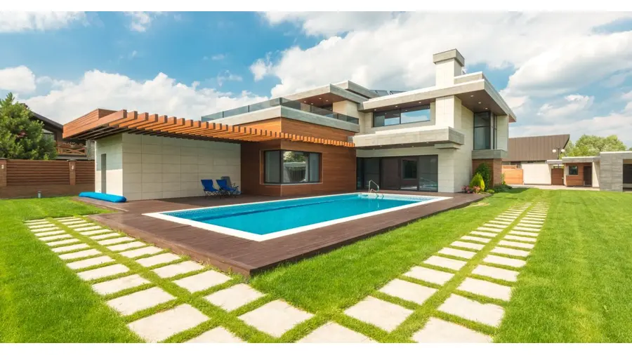 Contemporary house with pool, green lawn, and clear sky view.