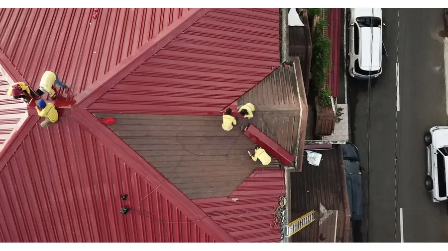 Aerial view of workers repairing a red metal roof in Quezon City, Philippines.